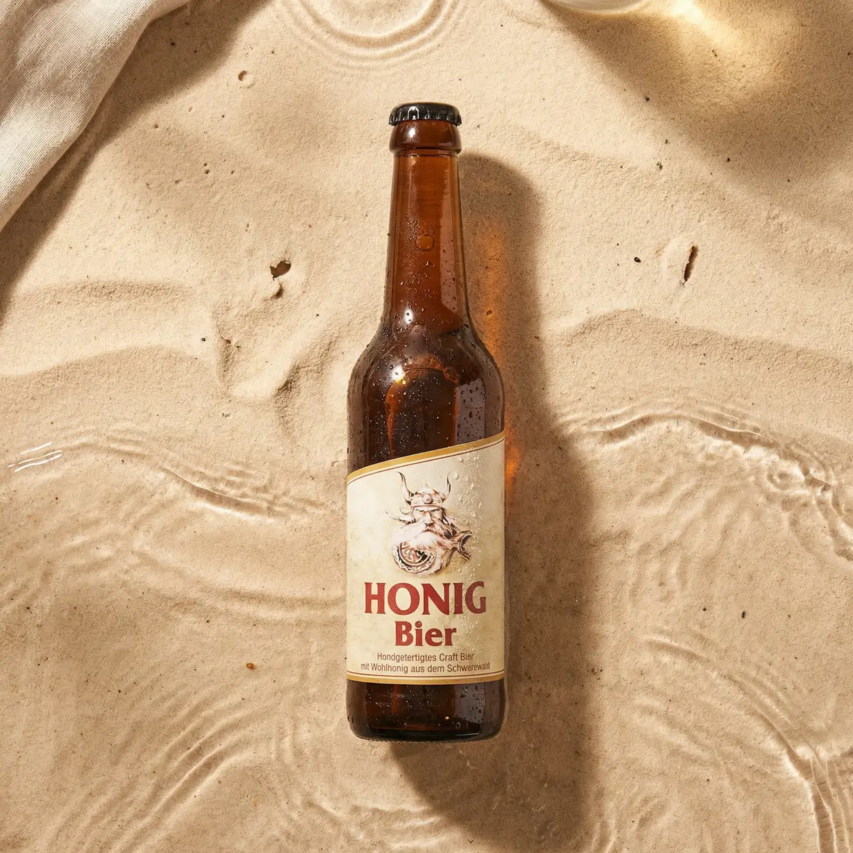 Eine Flasche Honigbier liegt im Sand