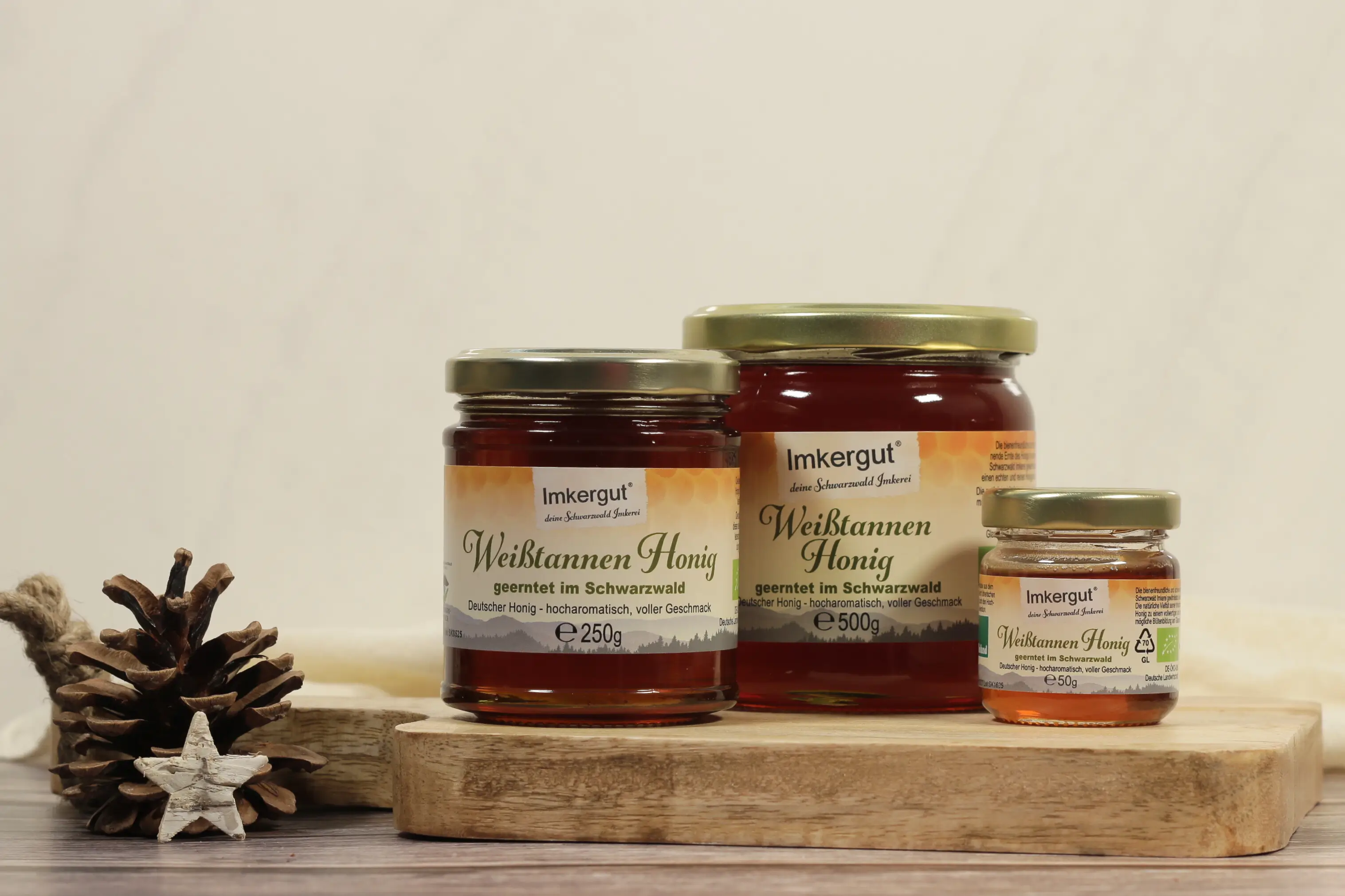 Drei verschieden große Gläser Weißtannenhonig auf einem Holzbrett