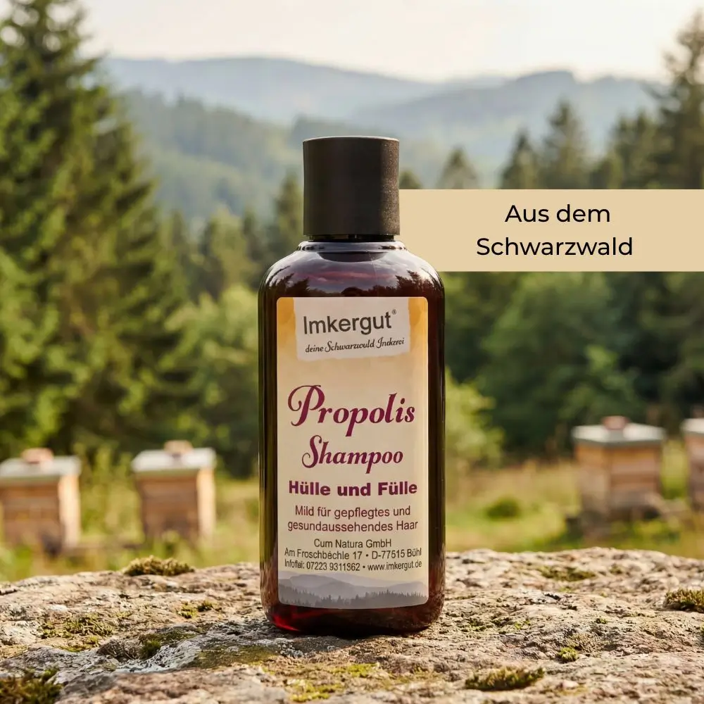 Eine Flasche Propolis Shampoo steht auf einem Stein vor einer Schwarzwaldkulisse mit Bäumen und Bienenstöcken, im Bild steht der Text „Aus dem Schwarzwald“