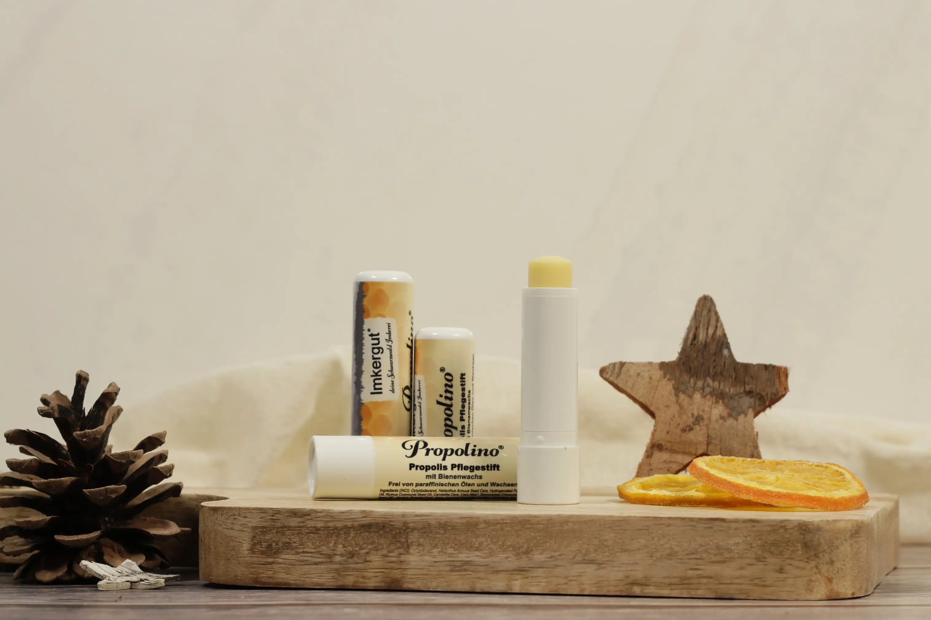 Mehrere Propolino-Lippenpflegestifte mit Bienenwachs auf einem Holzbrett