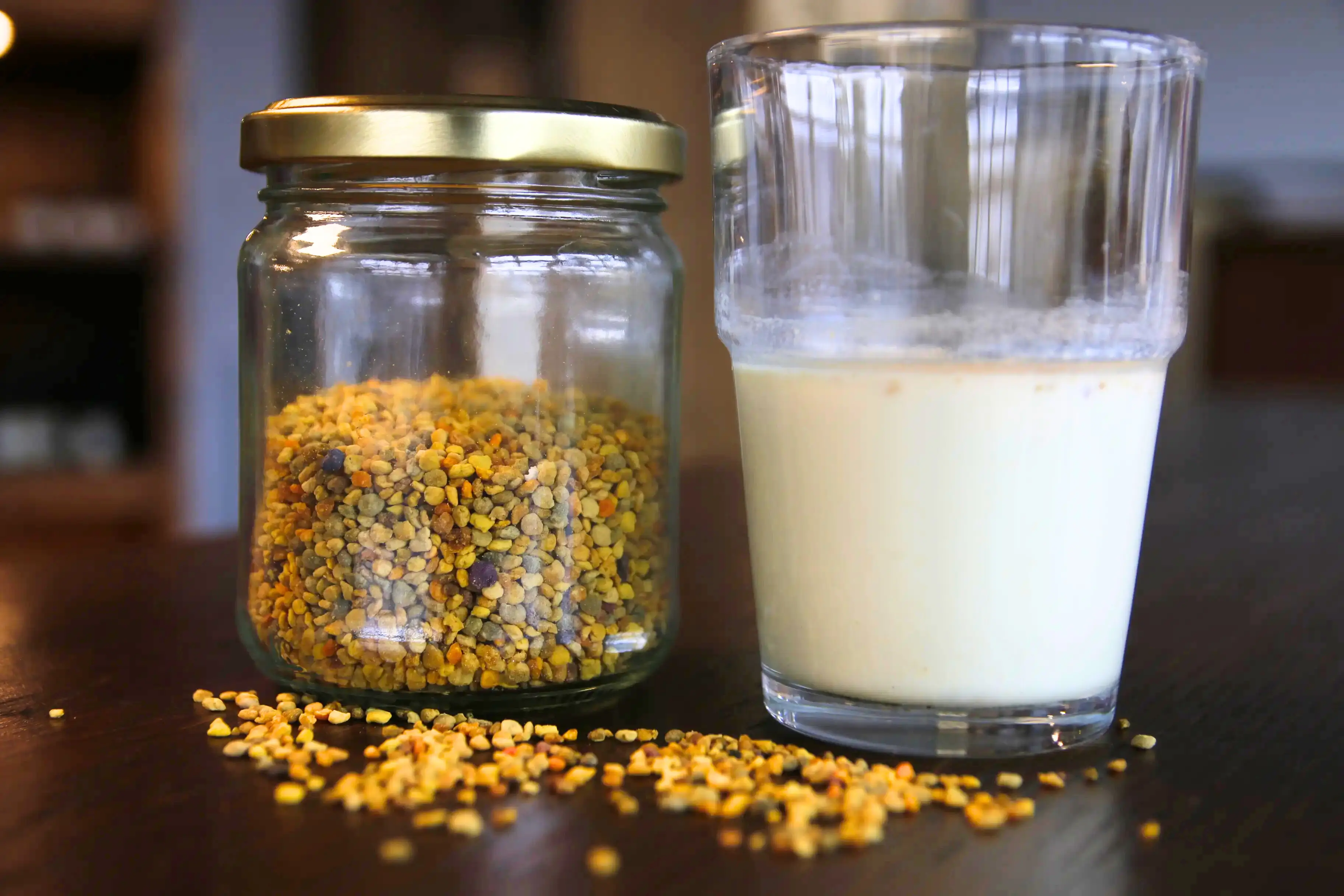 Blütenpollen und Milch Ein Glas Blütenpollen neben einem Glas Milch