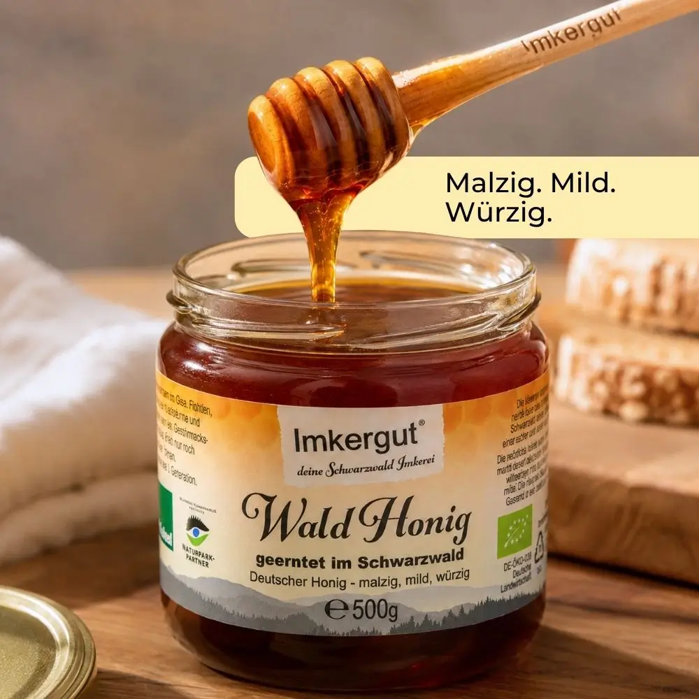 Geöffnetes Glas Imkergut Waldhonig 500g mit Honiglöffel, dunklem Waldhonig und Hinweis auf den malzig-milden, würzigen Geschmack.