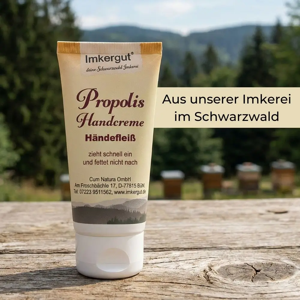 Propolis Handcreme auf rustikalem Holztisch vor Schwarzwald Landschaft mit Bienenstoecken, natuerliche Herkunft und Imkerei