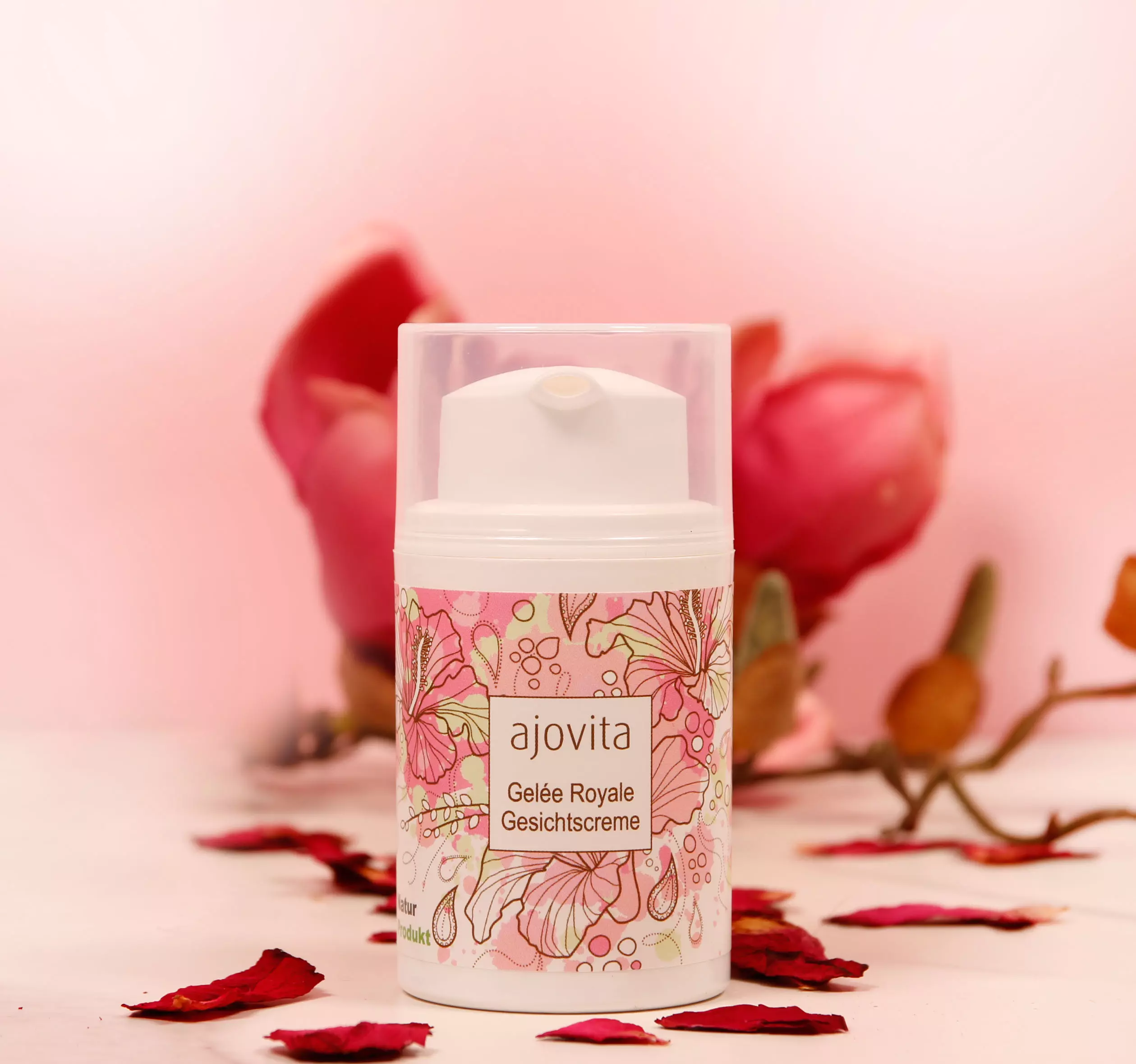 Gelée Royale Creme vor rosa Hintergrund mit Rosenblättern und einer Blüte