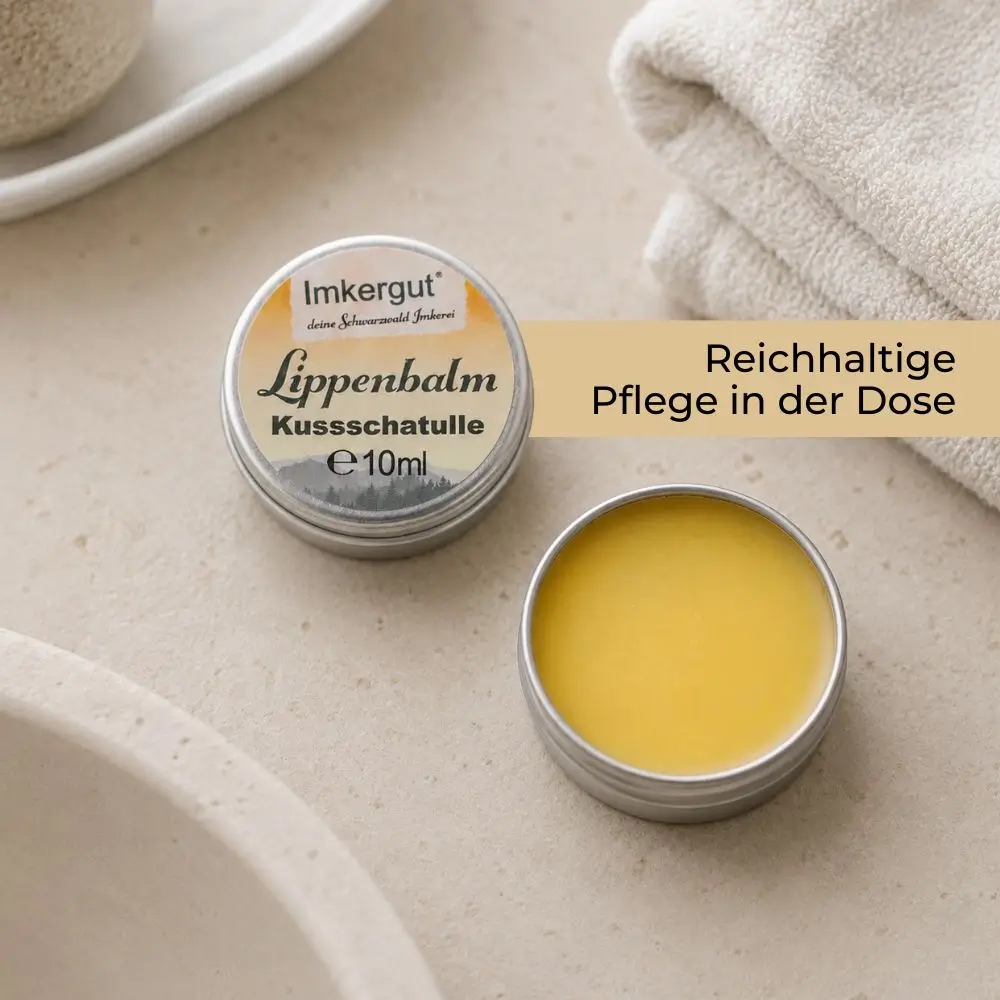 Geöffnete Imkergut Lippendose mit gelber Balm-Textur in einem hellen Badezimmer-Setting mit Handtuch im Hintergrund.