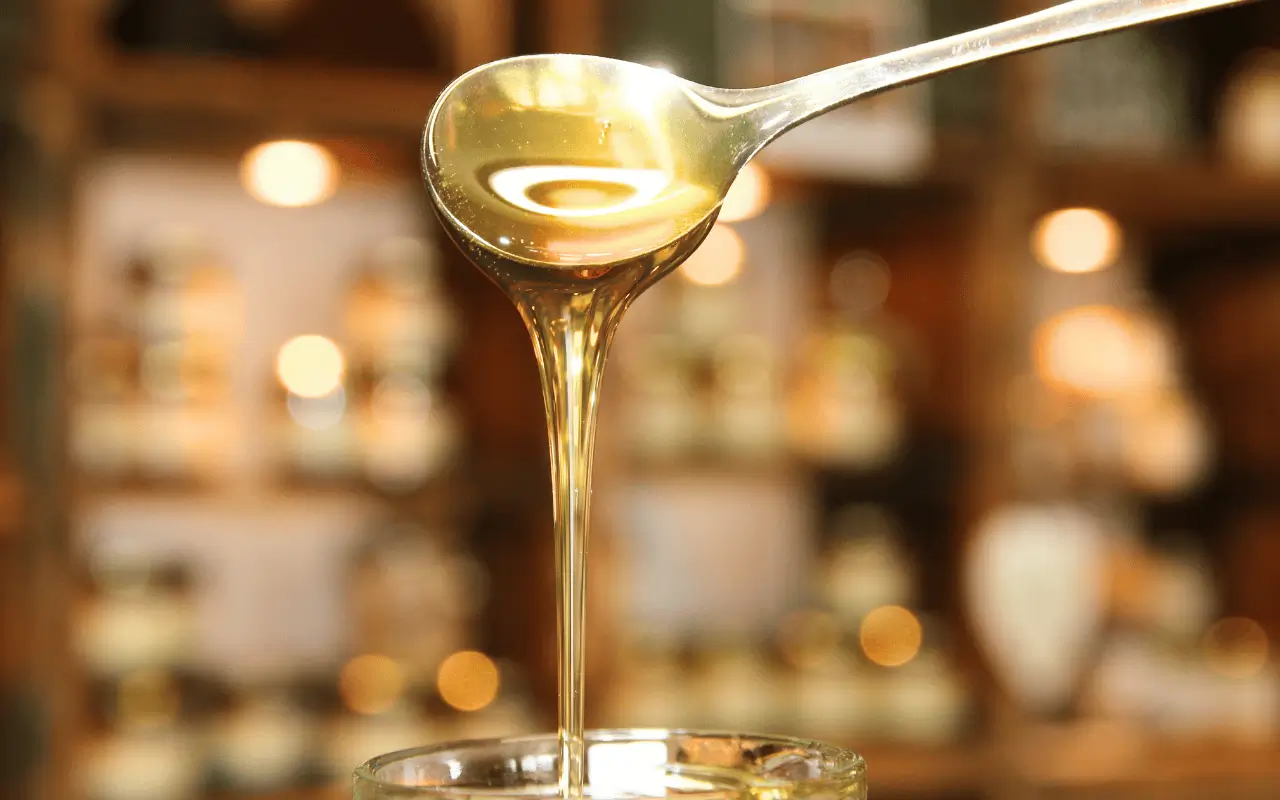 Ein Löffel, von dem flüssiger Honig fließt